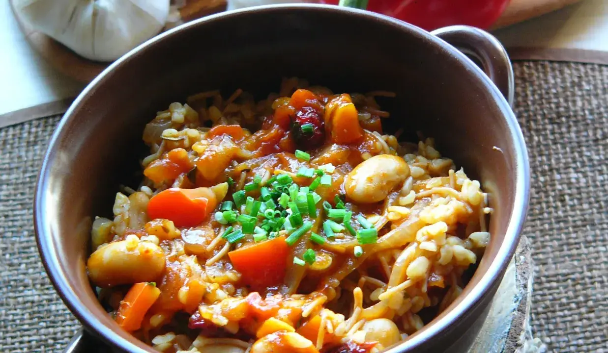 Pyszna kasza bulgur gotowanie z warzywami i fasolą, posypana szczypiorkiem. Aromatyczne danie, które zachwyca smakiem.