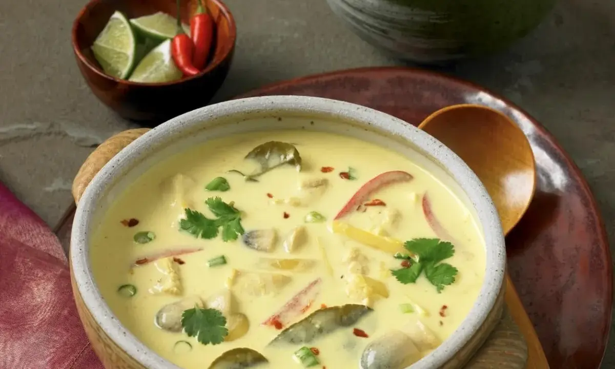 Aromatyczna zupa tajska z kurczakiem i mlekiem kokosowym, ozdobiona kolendrą i papryczkami chili.