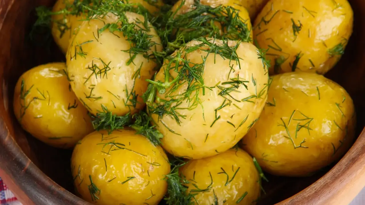 Ziemniaki gotowane w drewnianej misce, posypane świeżym koperkiem. Aromatyczne i apetyczne danie.
