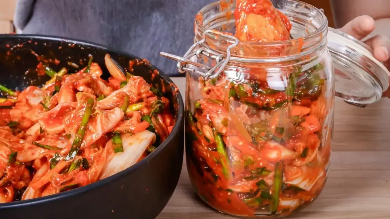 Domowe kimchi w słoiku i misce, przygotowywane z kapusty i przypraw.