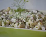 Pyszna sałatka z makaronem, szynką, ogórkiem i serem, udekorowana świeżym koperkiem.