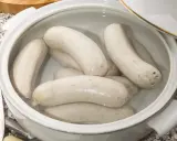 Biała kiełbasa w garnku z wodą, gotowa do parzenia. Idealny sposób, jak sparzyć białą kiełbasę, by była soczysta i smaczna.