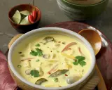 Aromatyczna zupa tajska z kurczakiem i mlekiem kokosowym, ozdobiona kolendrą i papryczkami chili.