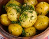 Ziemniaki gotowane w drewnianej misce, posypane świeżym koperkiem. Aromatyczne i apetyczne danie.