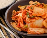 Miseczka z kimchi, obok ryżu i pałeczek.