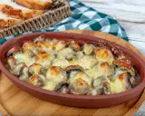 Pieczarki zapiekane z serem w glinianym naczyniu, obok koszyk z pieczywem.