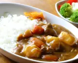 Pyszny ryż z curry, z kawałkami mięsa, ziemniaków i marchewki, podany z surówką.