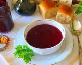 Aromaticzny barszcz czerwony z surowych buraków, podany z bułeczkami i słoikiem domowych przetworów.