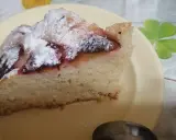 Pyszne ciasto z mrożonymi śliwkami, posypane cukrem pudrem, na żółtym talerzyku. Idealne na deser.