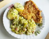 Kotlet schabowy z ziemniakami i młodą kapustą zasmażaną z boczkiem.