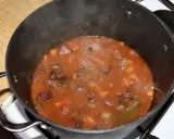 Gorący gulasz z dzika po myśliwsku bulgocze w garnku. Aromatyczny sos z kawałkami mięsa i warzyw.