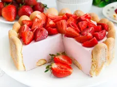 Sernik na zimno stary przepis, udekorowany świeżymi truskawkami i biszkoptami. Puszysty, różowy deser zachwyca wyglądem i smakiem.