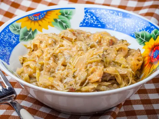 Młoda kapusta z koperkiem w misce z motywem słoneczników, obok widelca.