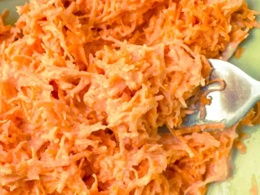 Tarta marchewka z majonezem, idealna jako surówka do obiadu. Widoczna łyżka widelca zagłębia się w pomarańczową masę.