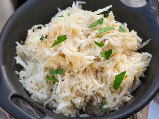 Pyszna sałatka z selera świeżego, posypana natką pietruszki i ziarnami gorczycy, w czarnej misce.