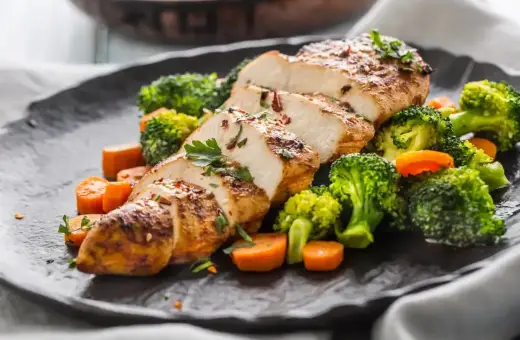 Soczysty filet drobiowy pokrojony w plastry, podany z chrupiącym brokułem i marchewką.