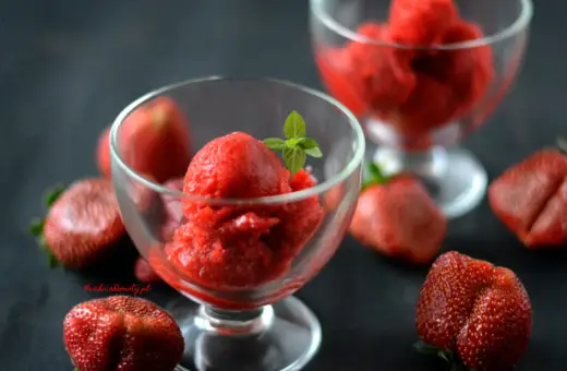 Jak zrobić sorbet truskawkowy? Pyszny, orzeźwiający deser w pucharkach, otoczony świeżymi truskawkami. Idealny na upalne dni.