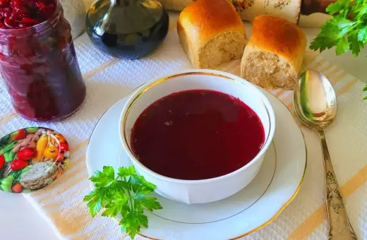 Aromaticzny barszcz czerwony z surowych buraków, podany z bułeczkami i słoikiem domowych przetworów.