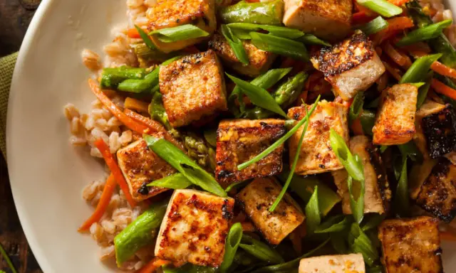 Chrupiące kostki tofu z warzywami i kaszą na talerzu.