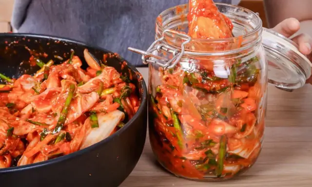 Domowe kimchi w słoiku i misce, przygotowywane z kapusty i przypraw.