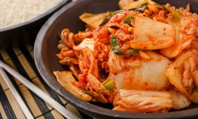 Miseczka z kimchi, obok ryżu i pałeczek.