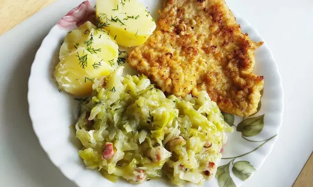 Kotlet schabowy z ziemniakami i młodą kapustą zasmażaną z boczkiem.