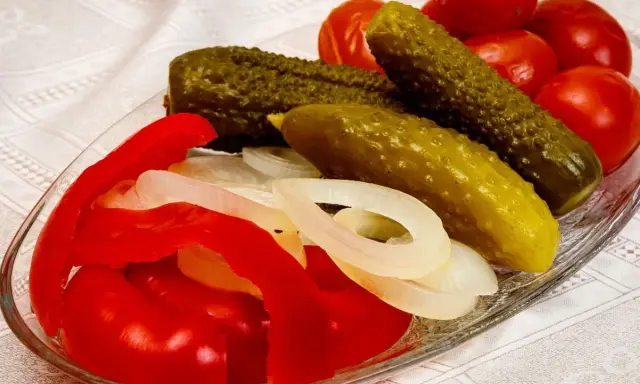 Ogórki, pomidory, papryka i cebula na talerzu.