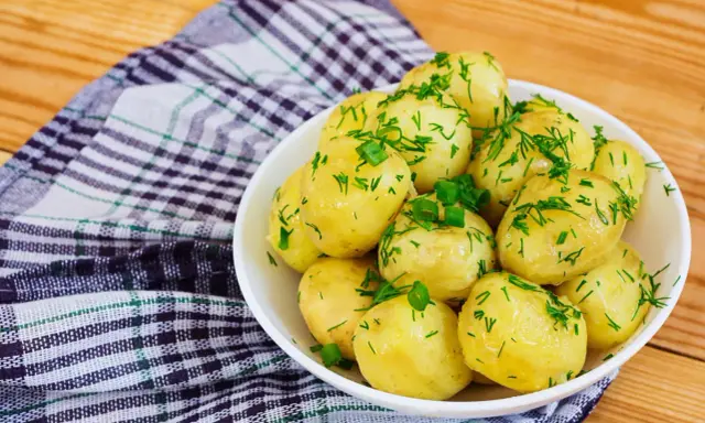 Młode ziemniaki w misce, posypane koperkiem i szczypiorkiem. Idealne na lato, a ile gotować młode ziemniaki? Krótko!