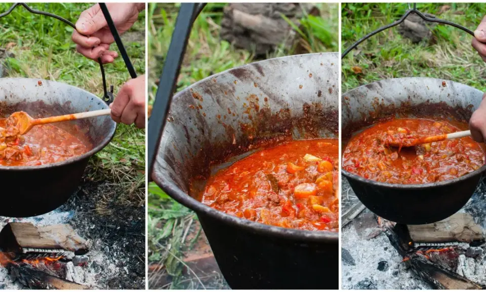 Gotowanie aromatycznego bogracza nad ogniskiem. Mieszanie drewnianą łyżką gęstej, czerwonej potrawy w kociołku.