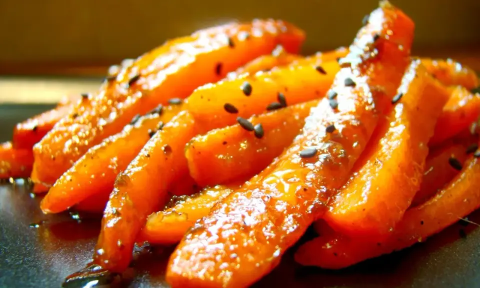 Apetyczna, glazurowana marchewka z czarnym sezamem, błyszcząca od miodowej glazury.