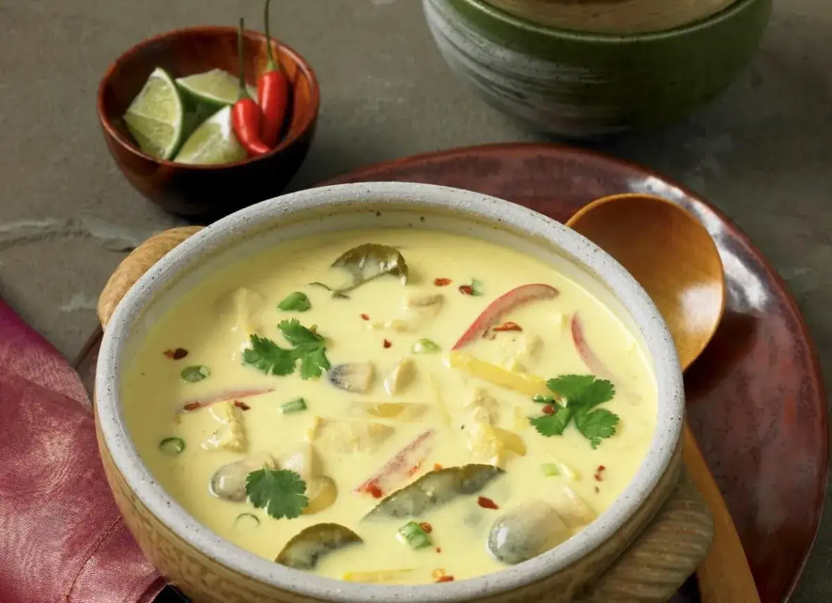 Aromatyczna zupa tajska z kurczakiem i mlekiem kokosowym, ozdobiona kolendrą i papryczkami chili.