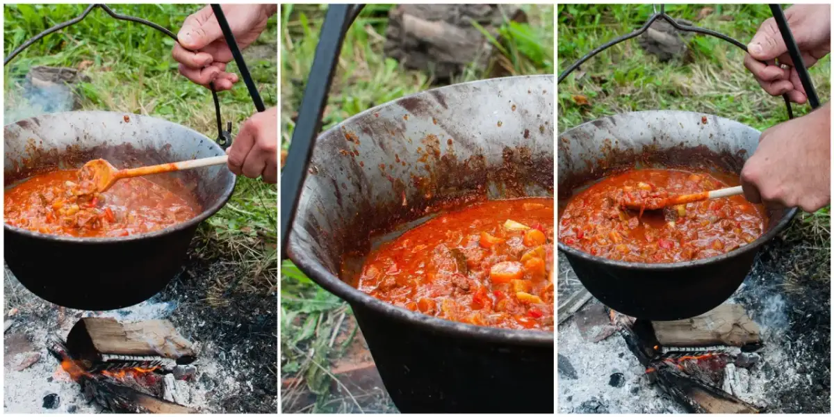 Gotowanie aromatycznego bogracza nad ogniskiem. Mieszanie drewnianą łyżką gęstej, czerwonej potrawy w kociołku.