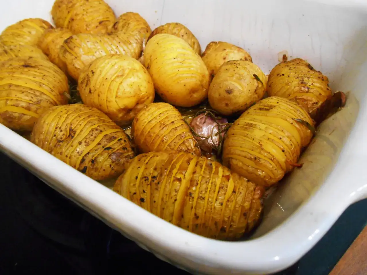 Złociste, nacięte ziemniaki Hasselback w naczyniu żaroodpornym, gotowe do podania. Szybki przepis na pieczone ziemniaki, idealny na obiad.