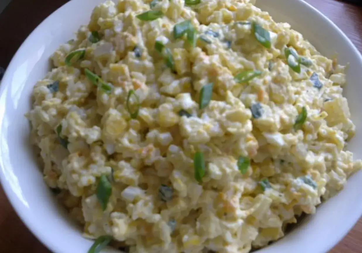 Szybka sałatka z ryżem i jajkiem, z dodatkiem szczypiorku, w białej misce. Idealna na szybki lunch.