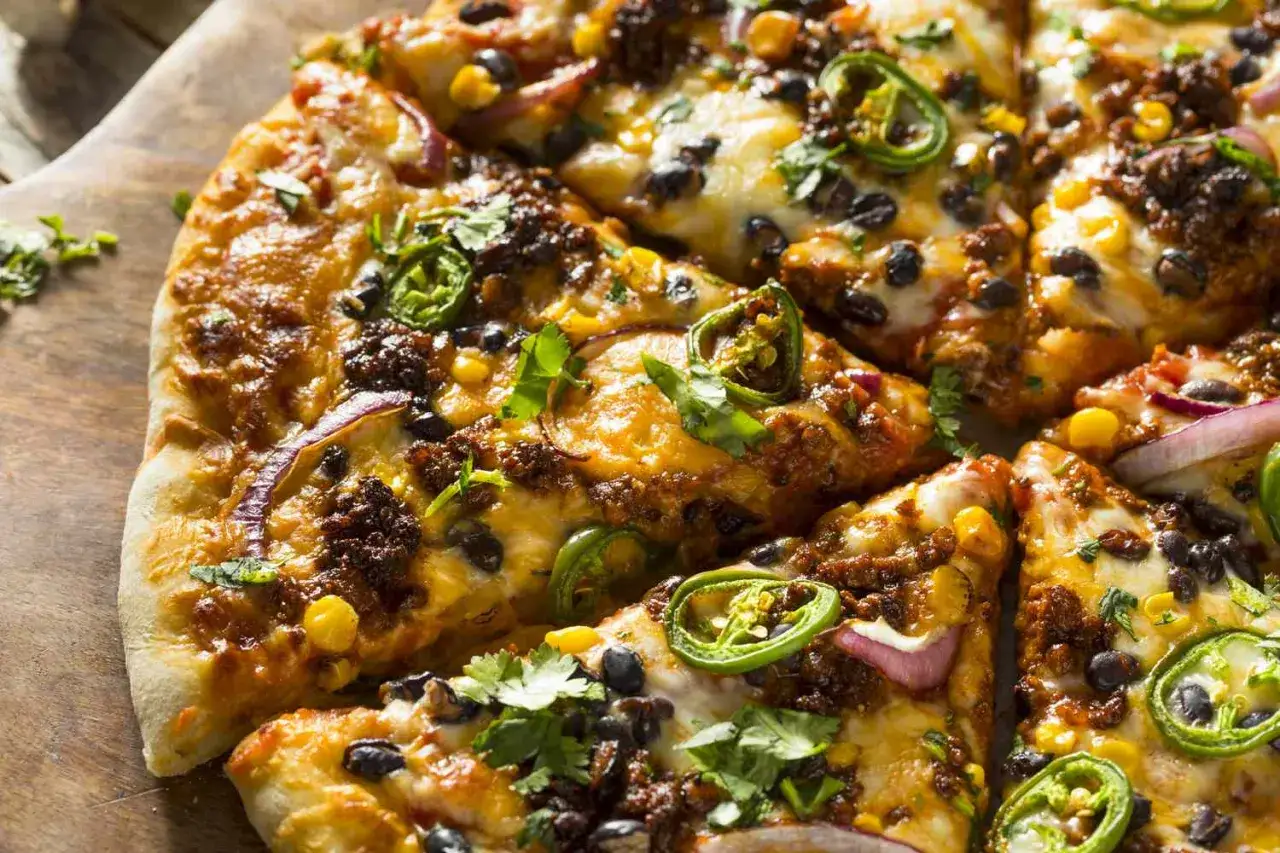 Gotowe ciasto na pizzę z mielonym mięsem, fasolą, kukurydzą, jalapeño i czerwoną cebulą, posypane świeżą kolendrą.