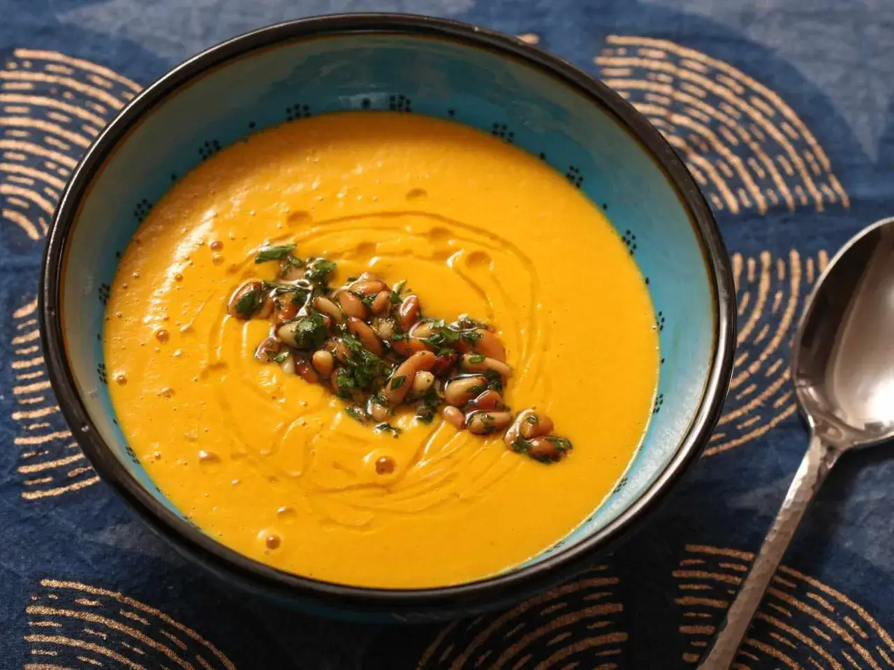 Pomarańczowe puree z dyni, ozdobione prażonymi orzeszkami pinii i natką pietruszki. Idealne na jesienne dni, gdy chcesz wiedzieć, jak zrobić puree.