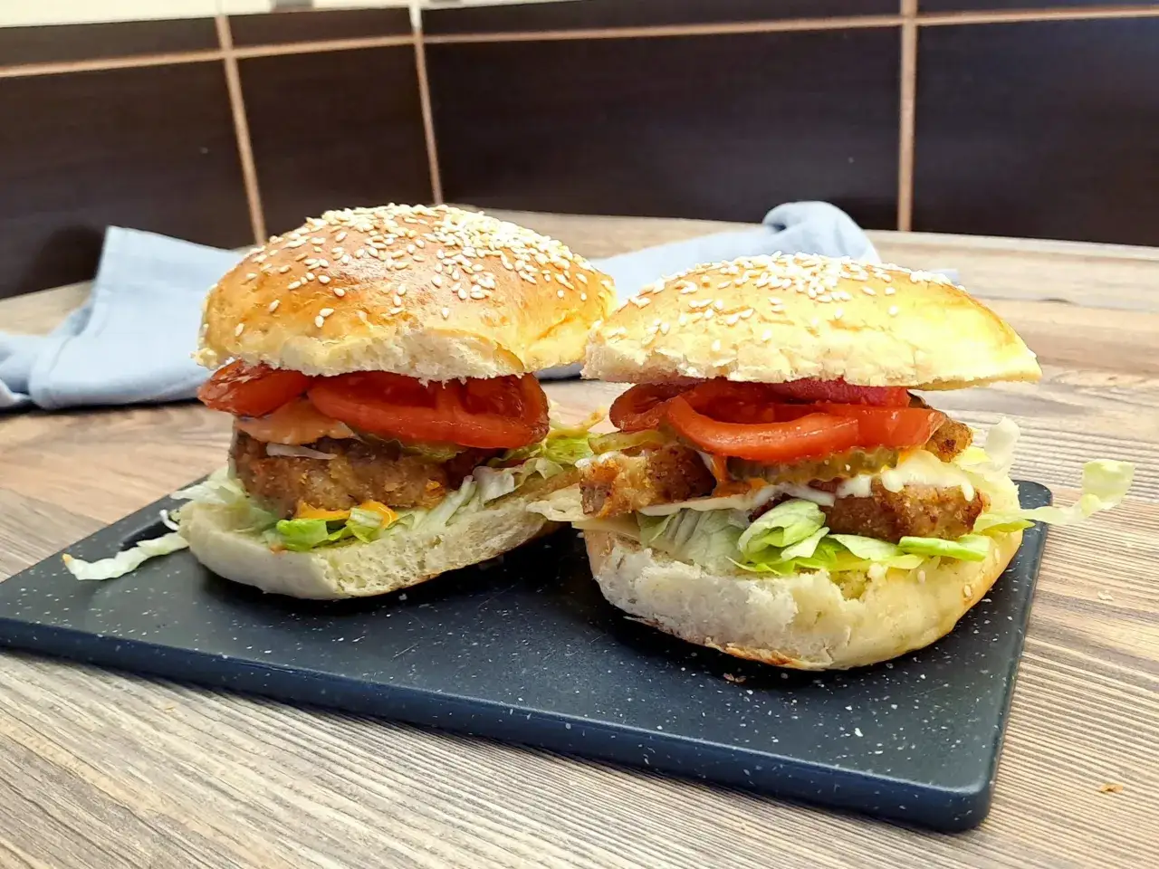 Dwa soczyste burgery wieprzowe z sezamową bułką, chrupiącą sałatą, pomidorami i ogórkiem kiszonym.