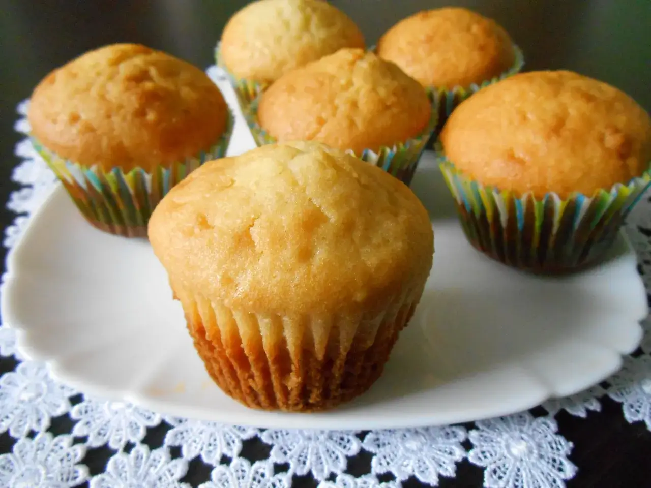 Kilka pysznych, złotych muffinek na białym talerzyku. Idealne na dobry przepis na muffinki.